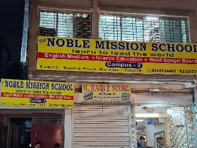 Night view of The Noble Mission School Campus 2 building facade with yellow school banners